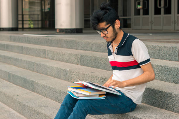 istock young charming guy is sitting on the stairs and reads books 847632772