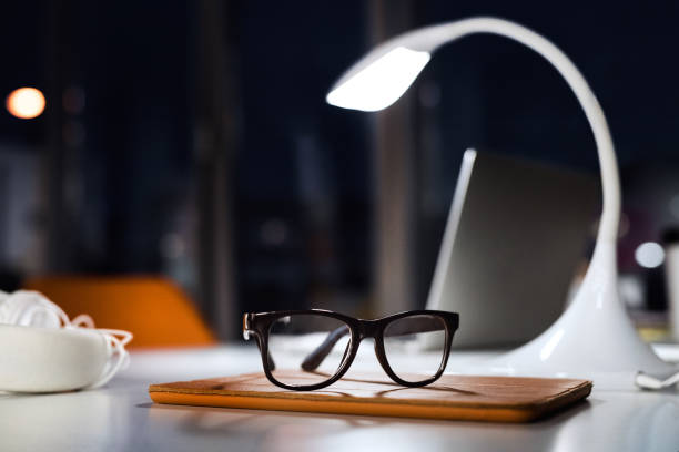 istock Office desk at night with eyeglasses, lamp and tablet. 847633556