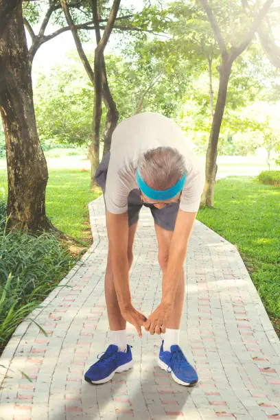 Picture of an elderly man wearing sportswear while doing a workout in the park