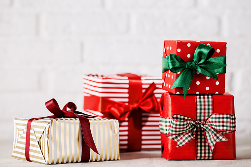 Colorful wrapped giftboxes decorated with ribbons and arranged together on white studio background.