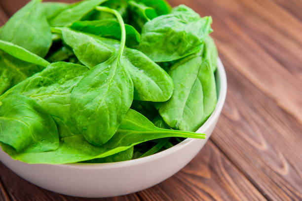 istock Fresh spinach leaves with water drops in ceramic bowl on the dark rustic wooden background. Selective focus. Space for text. 847636446