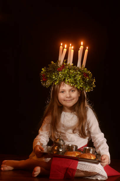 Little caucasian girl in Saint Lucia costume Little caucasian girl in Saint Lucia costume with crown of candles and traditional swedish sweet cirque de soleil stock pictures, royalty-free photos & images