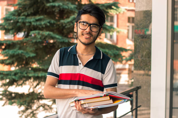 istock smiling guy in glasses looks into the camera and keeps the books 847641658