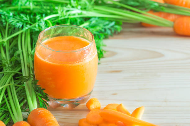 istock Fresh carrot juice in glass on wooden table with copy space 847648596