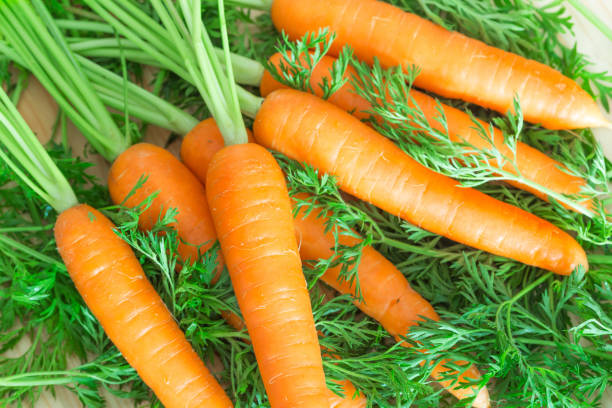 istock Bunch of fresh carrots on wooden background 847648610