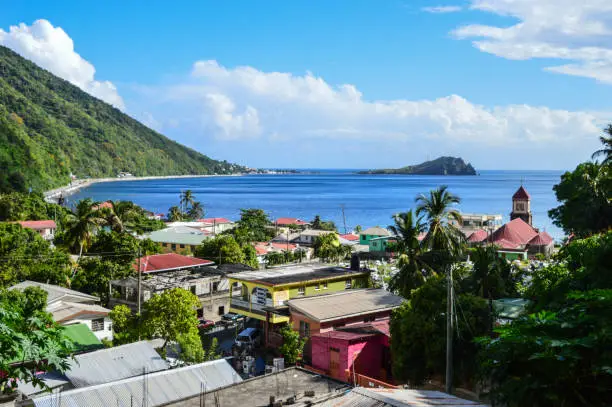 Soufriere, Dominica - May 17, 2017: colourful houses and church with Soufriere bay and Scott's Head in background