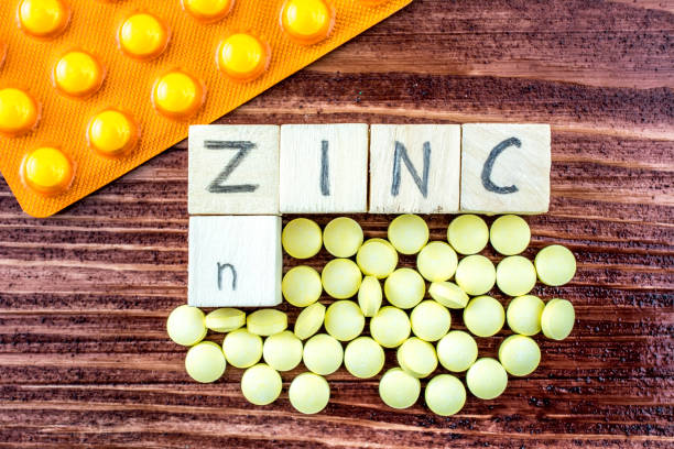 Yellow pills and blister pack on a wooden table - symbolizing zinc stock photo
