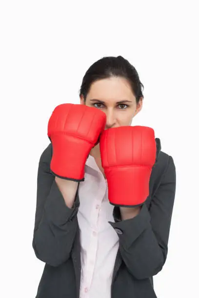 Combative brunette wearing red gloves against white background