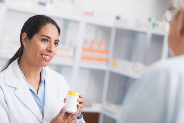 istock Pharmacist holding a drug box while looking at a patient 847670960