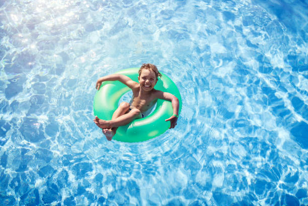 Cute little girl in blue inflatable circle swims in the pool. Summer concept