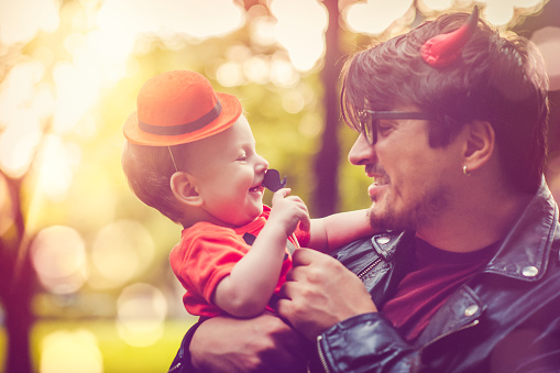 Father and his cute son dressed as little pumpkin at Halloween