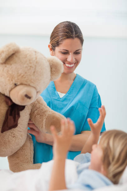 istock Smiling nurse showing a teddy bear to a child 847702420