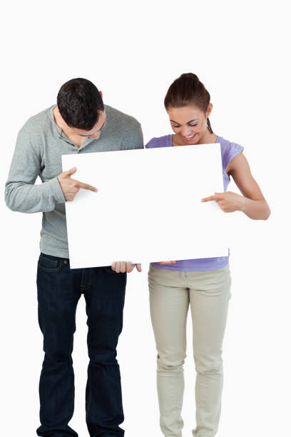 istock Young couple pointing at banner they are holding 847710018