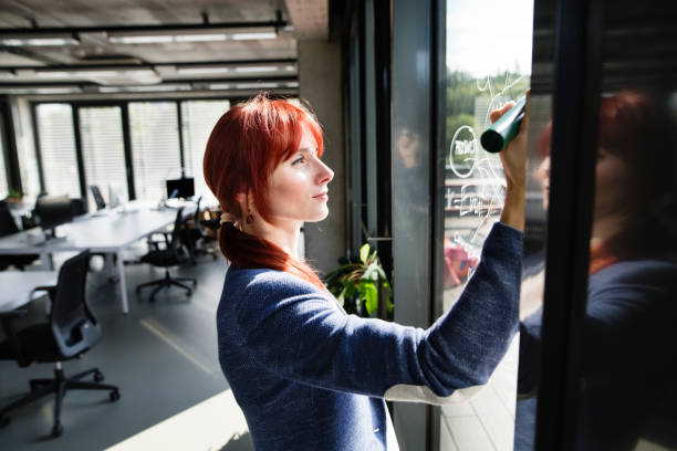 istock Businesswoman in her office writing note on window. 847713016