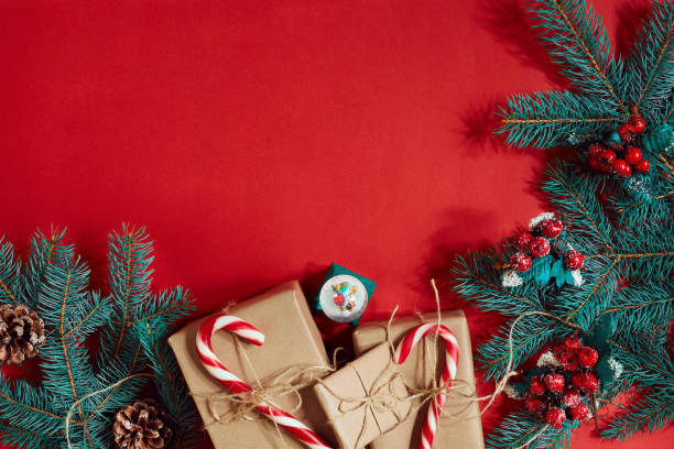 istock Christmas composition of pine cones, spruce branches and stack of gift boxes on red background 847714636