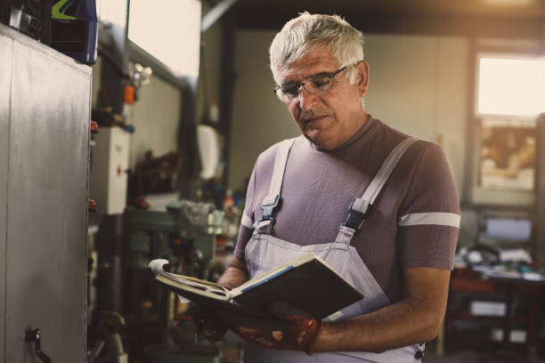 istock Senior man in workshop. Serious man writing in his planner book. 847717414