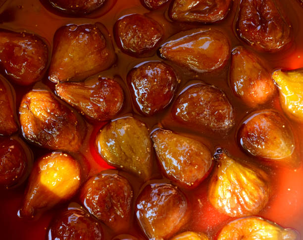 Fig jam or jelly cooking process. Brilliant figs in syrup, close-up. The fig jam is boiling, shiny berries in liquid.