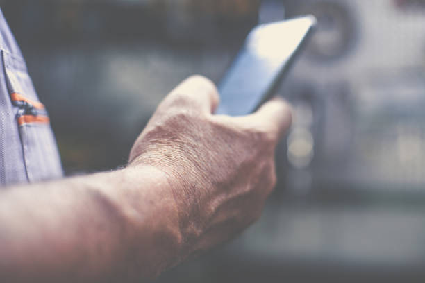 istock Senior man in workshop. Man holding mobile and reading text. Close up. 847718042