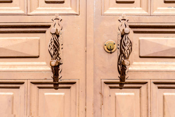Handcrafted metal door handles on a wooden front door with panels