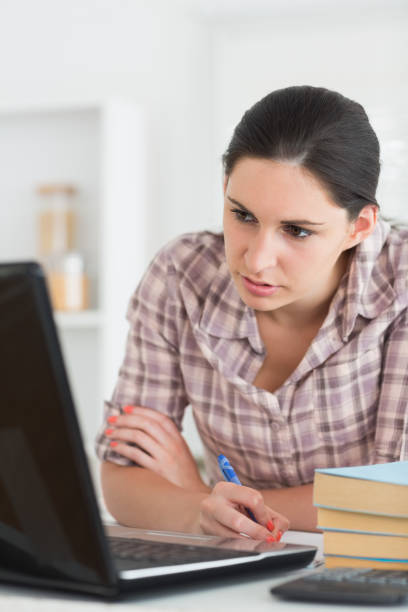 istock Woman writing on a notebook while looking at laptop 847724424