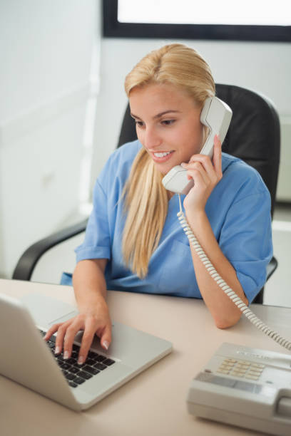 istock Nurse typing on a laptop while holding a phone 847734410