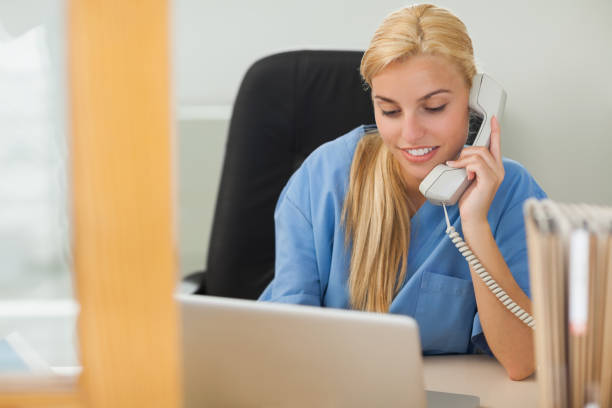 istock Blonde nurse calling next to a laptop 847734436