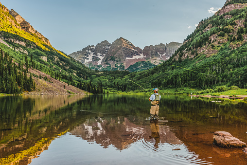 A fly fisherman makes a cast at sunset in the Maroon Bells wilderness near Aspen, Colorado.