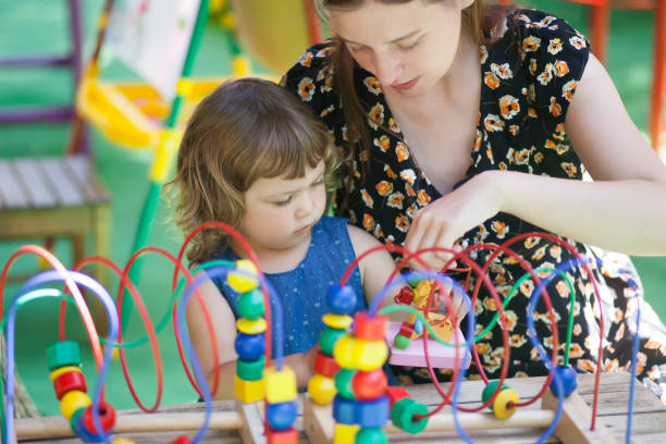 kleine mädchen und mutter mit bildungs-spielzeug zu spielen. - togetherness learning playful mother stock-fotos und bilder