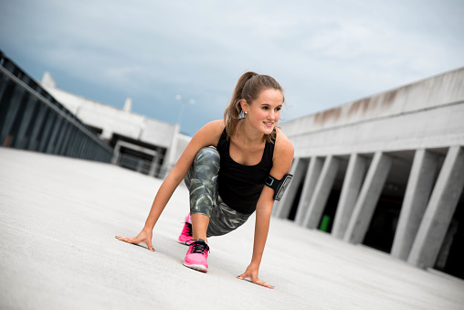 Young woman in sport clothes doing some stretching excersising outdoors on the concrete ground. Shot made in Ljubljana, Slovenia in September 2017.