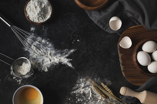flat lay with variety of bakery ingredients and kitchenware isolated on black table