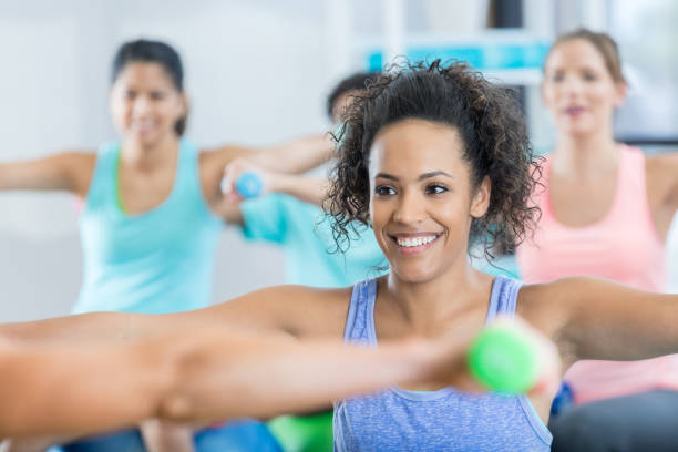 istock Smiling young woman works arms in weight training exercise class 847774062