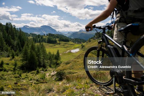 Young Adult Active Man On Mountain Wearing Bike Helmet And Backpack Looking At Scenic Panorama Holding Electric Bike In Sunny Summer Day Outdoor Stock Photo - Download Image Now