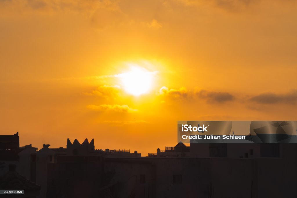 The city at the sunset. Birds flying at an orange sunset near the sea, in Essaouira. Aerial View Stock Photo