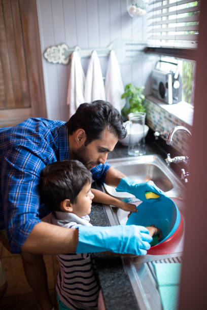 istock Father assisting son for cleaning utensils at home 847819592