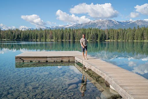 One young man walking on lake pier in summer, Canada.