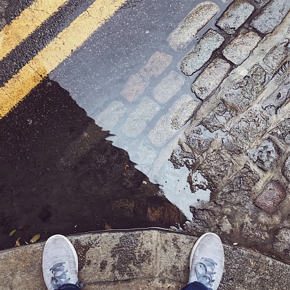 Looking down at feet in front of a puddle in Shoreditch London