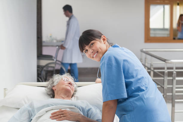 istock Smiling nurse leaning on the bed of a patient 847830588