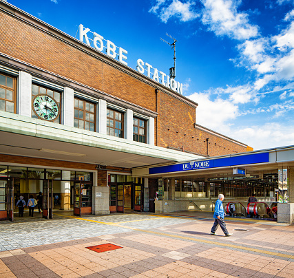 Kobe Japan train station and subway entrances with a few commuters walking in and out of the station on a sunny Springtime morning.