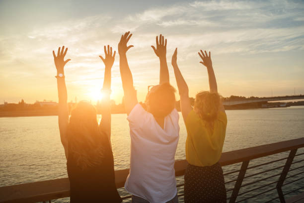 Three friends enjoying outdoors with hands in the air.