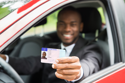 Happy Young African Businessman Showing His Driving License From Open Car Window