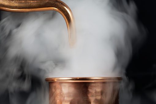 A copper pipe of a distillery with steam.