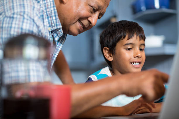 istock Close up grandfather assisting grandson using laptop 847866520