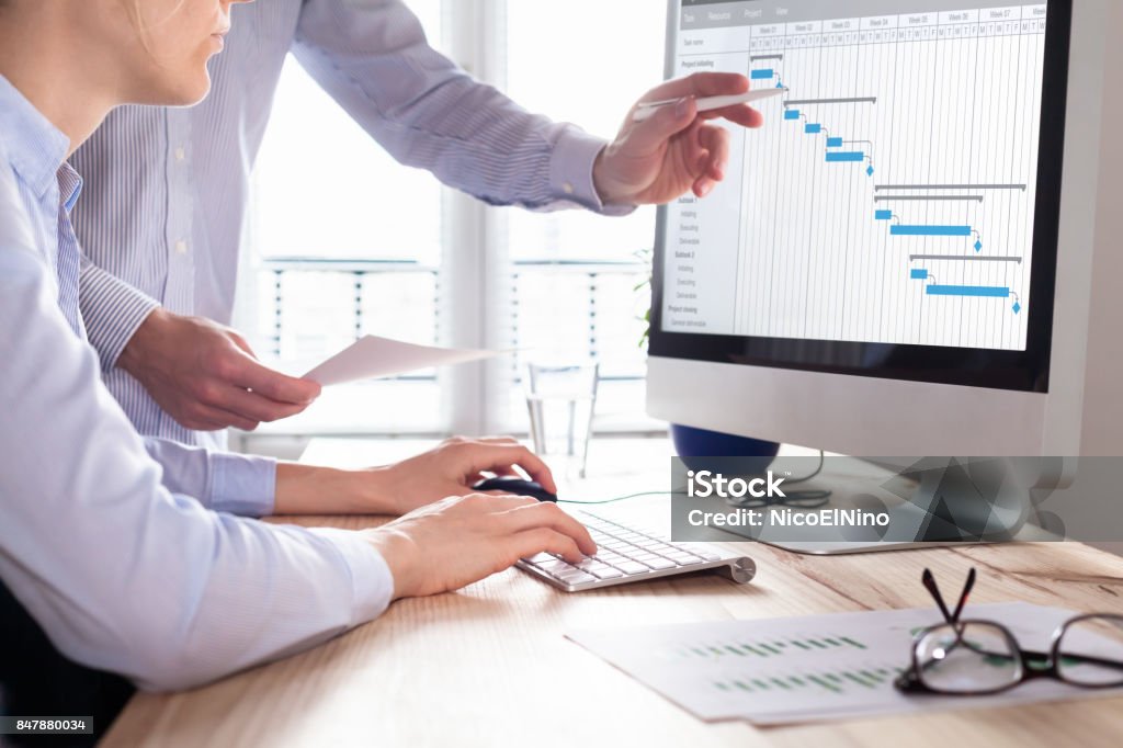 Project management team updating schedule or planning on computer, business Project management team updating Gantt chart schedule or planning on computer, two business people in office Project Management Stock Photo
