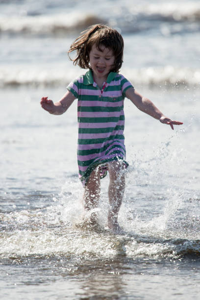 istock Young little girl on beach playing in the surf 847883880