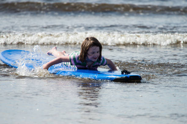 istock Young little girl on beach taking surfing lessons 847884640