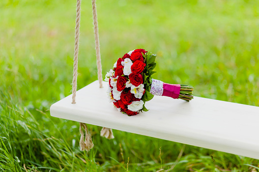 Bridal Bouquet Red and White Roses lying on a rope swing
