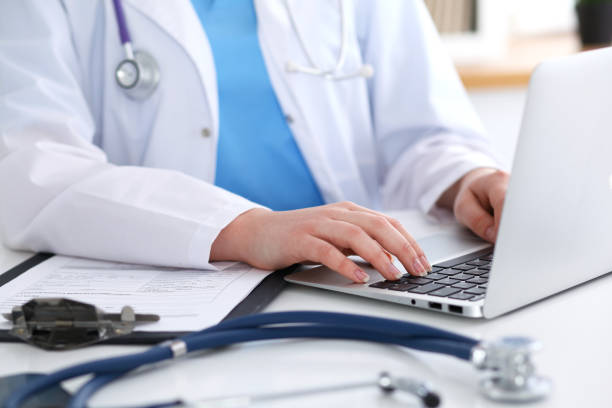 istock Close up of unknown female doctor typing on laptop computer while sitting  at the table 847909864