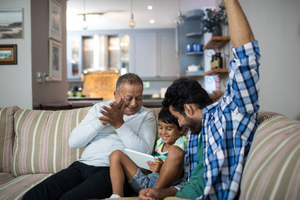 istock Happy grandfather and father with boy sitting on sofa 847913012