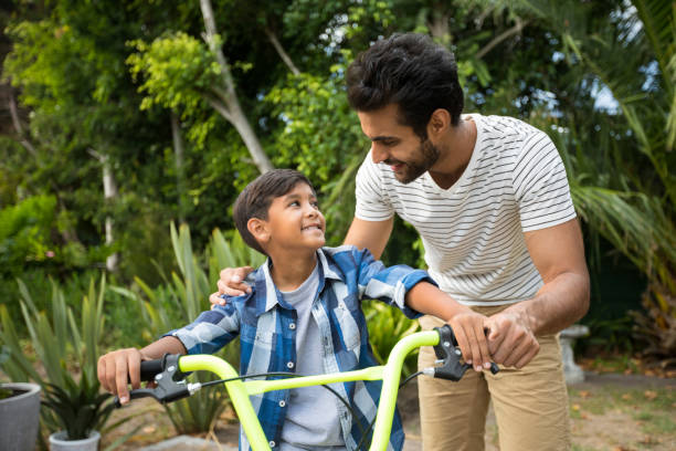 istock Father and son standing with bicycle while looking at each other 847963106
