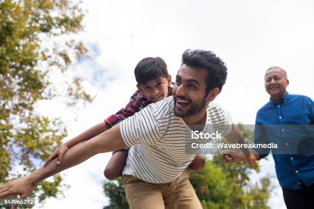 Happy Grandfather Looking At Man Giving Piggy Backing To Son Stock Photo - Download Image Now